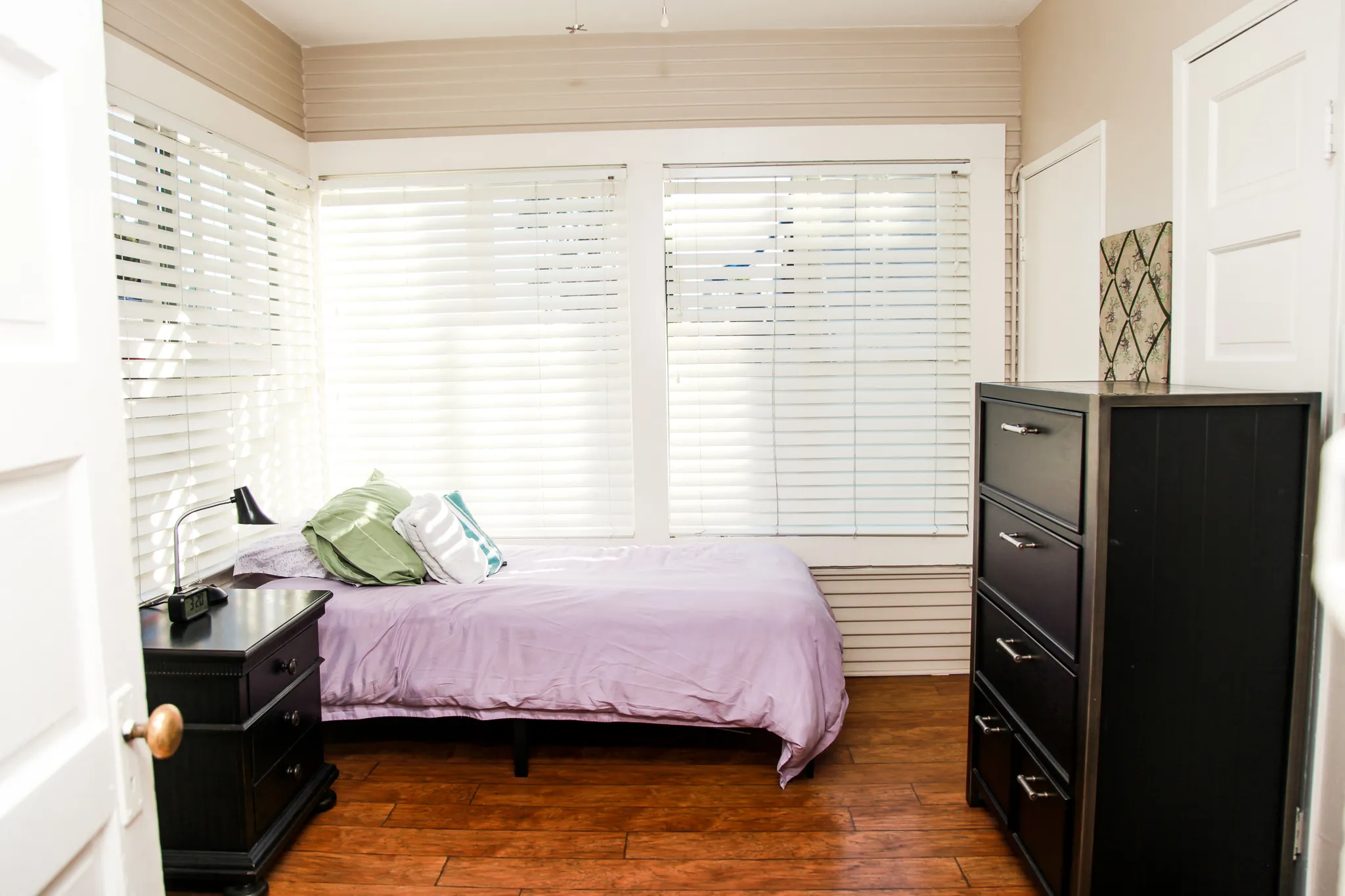 A resident's bedroom — a single bed, sunlight through the blinds, wood floors